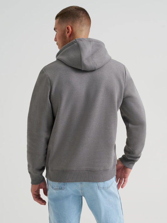 Man wearing a gray hoodie and light blue jeans on a plain background