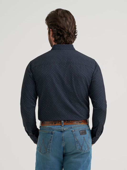 Man wearing a dark blue patterned Wrangler shirt and jeans on a light gray background