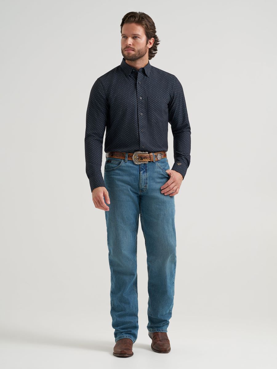 Man wearing a dark patterned Wrangler shirt and blue jeans on a white background