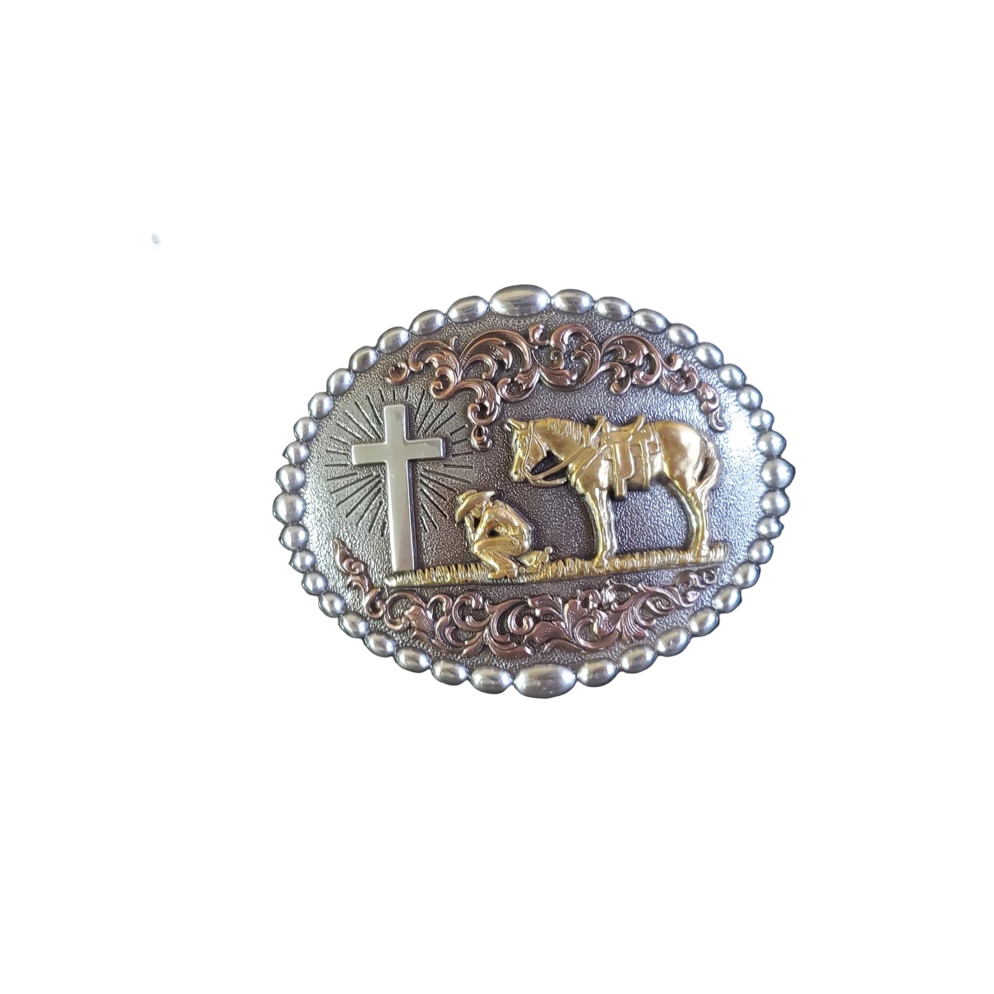 a silver belt buckle with a gold horse and cowboy praying by a cross