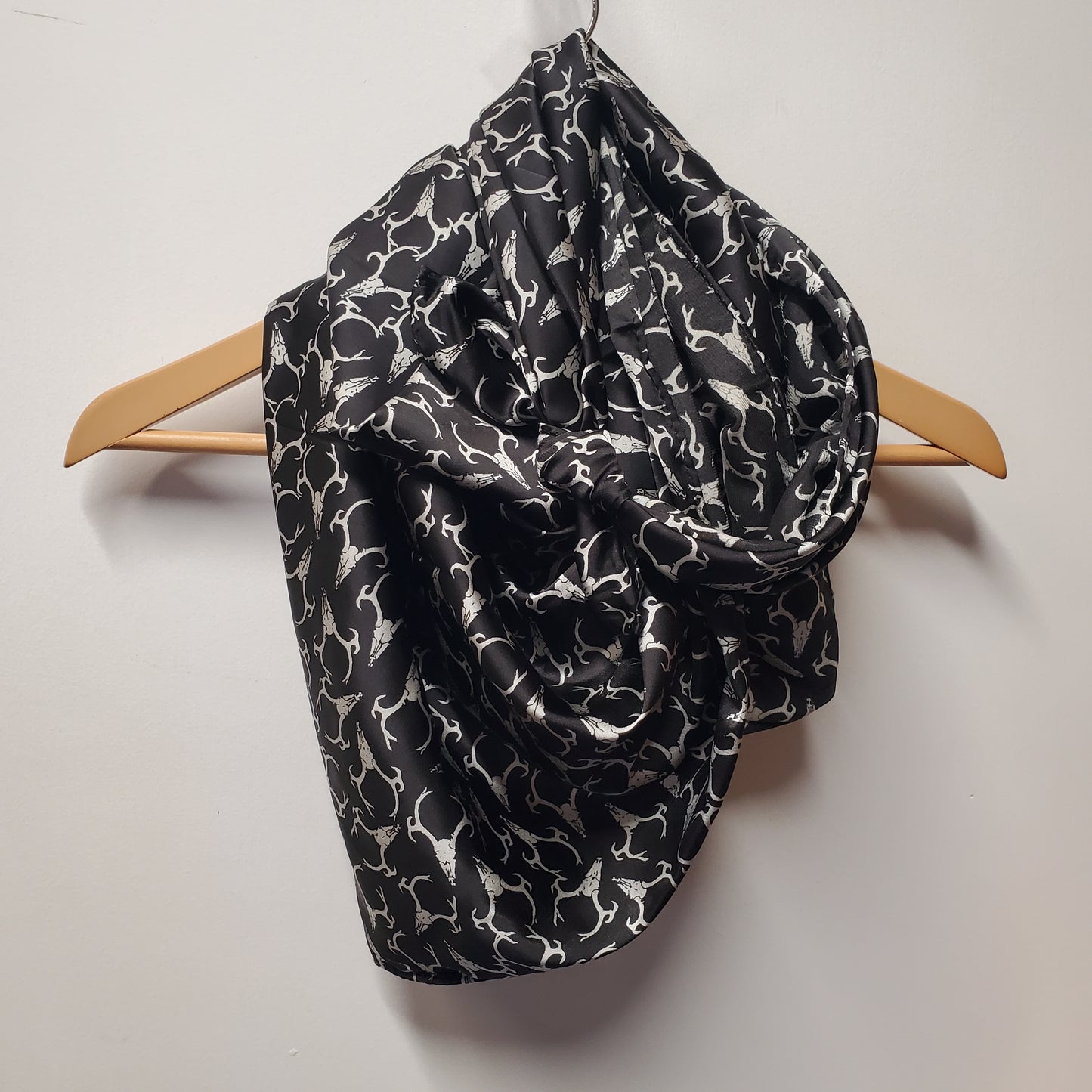 Silk scarf hanging on coat hanger with deer skull print on a white background