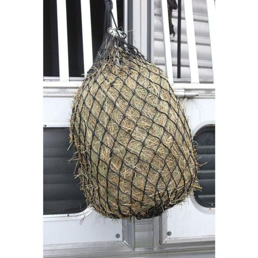 a black slow feed hay net full of hay hanging on a horse trailer