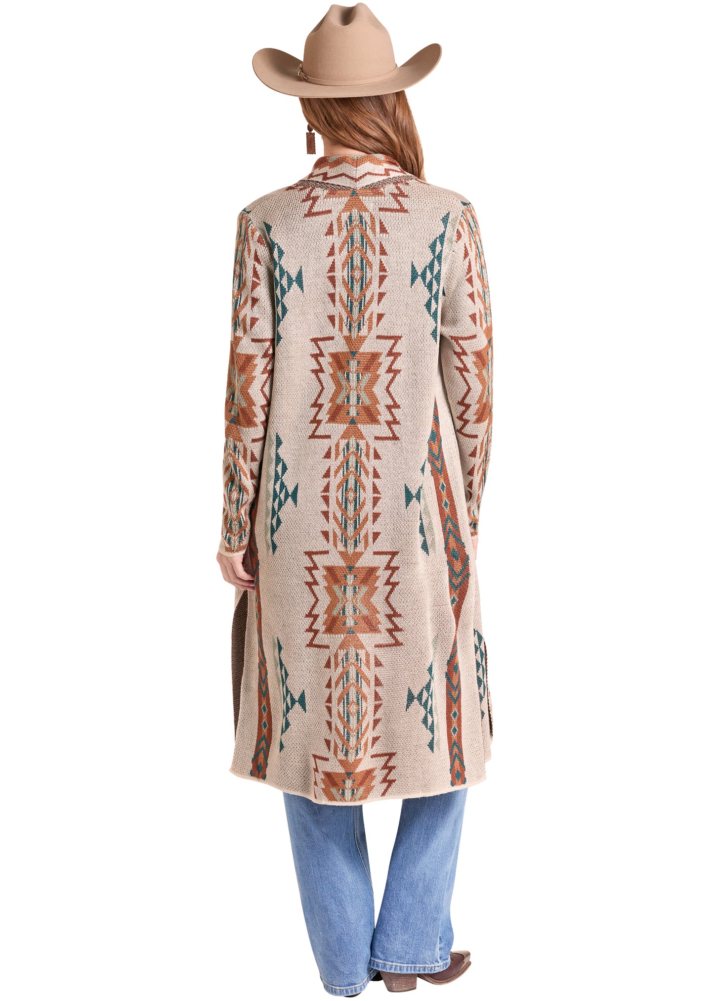 A woman shown from the back wearing a long Rock&Roll Denim beige cardigan with a Southwestern geometric pattern in rust orange, teal, and brown, paired with blue jeans and a tan cowboy hat on a white background.
