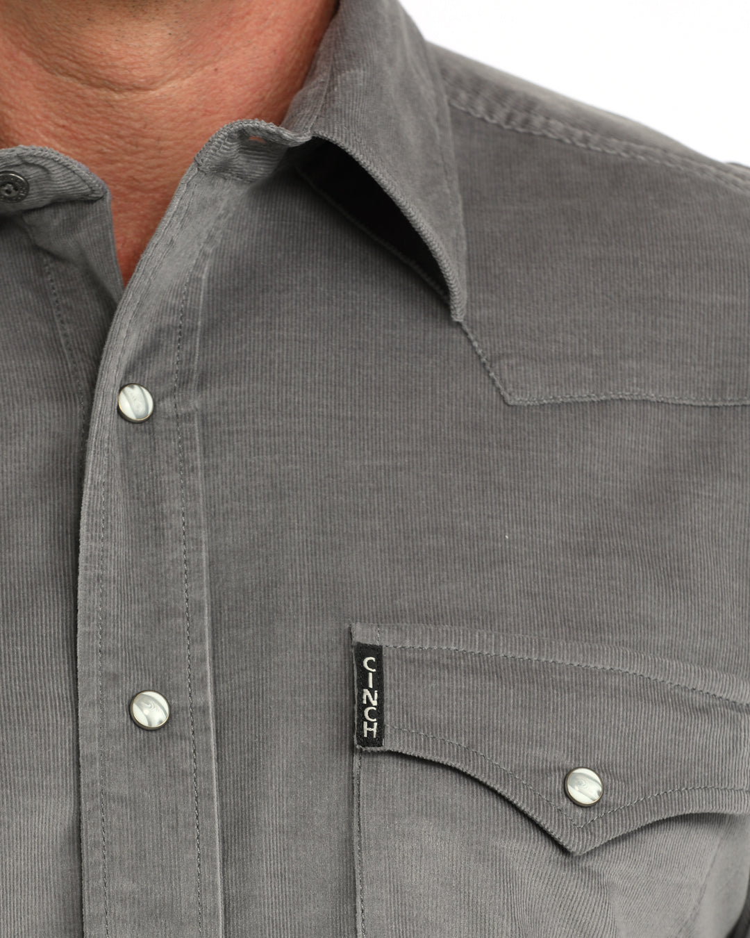 Close up of a man wearing a grey corduroy Cinch shirt on a white background
