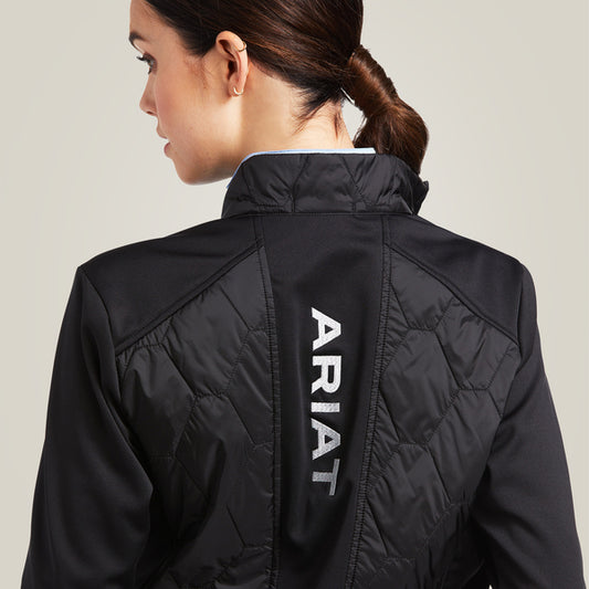 Woman wearing a black jacket with a visible Ariat logo on a light gray background
