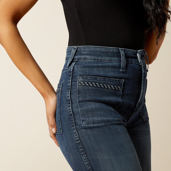 woman wearing blue Ariat jeans and a black t shirt on a cream background