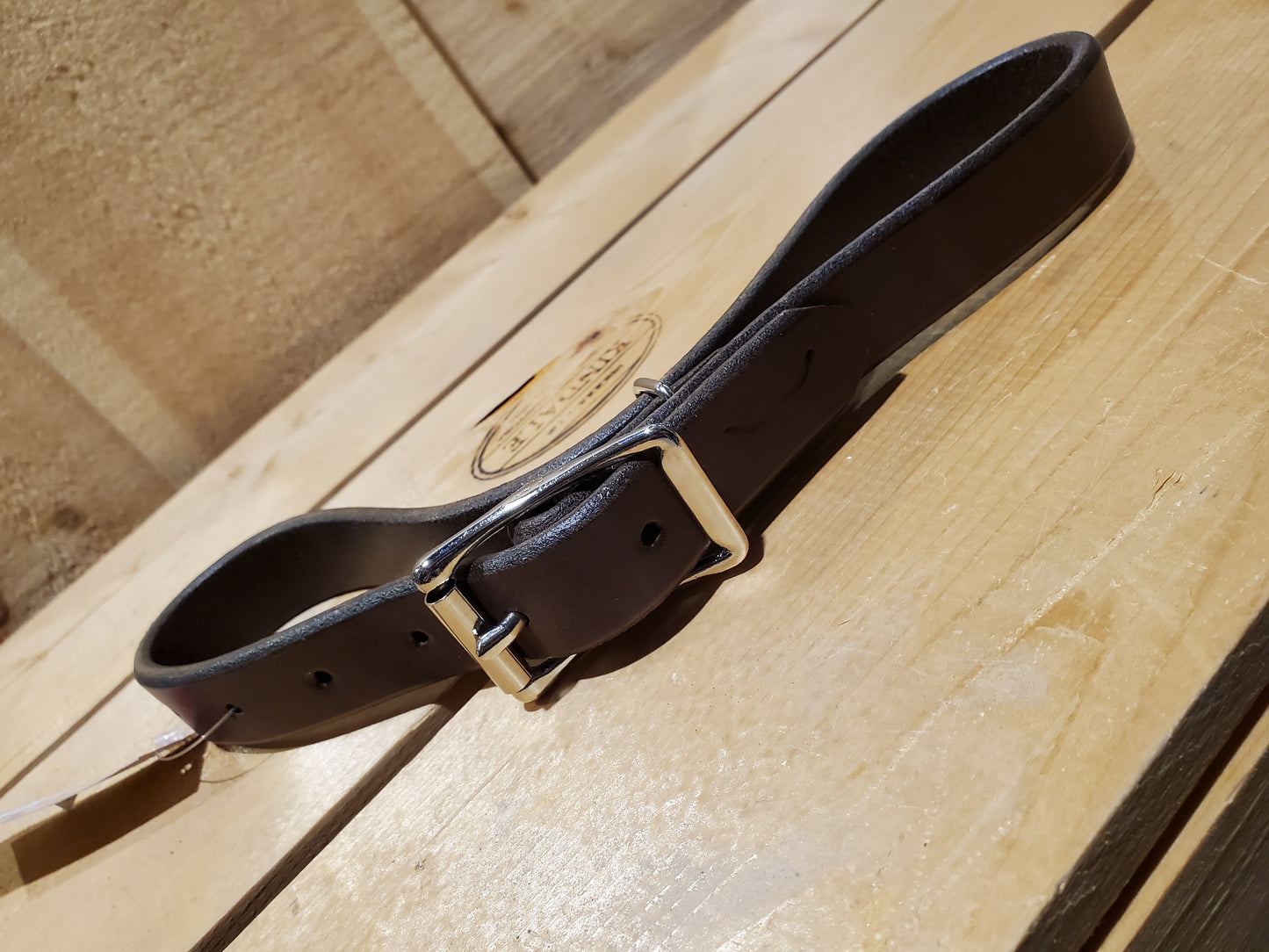 dark brown leather strap with a double bar roller buckle and a metal loop used as a breast collar tug for horse equipment