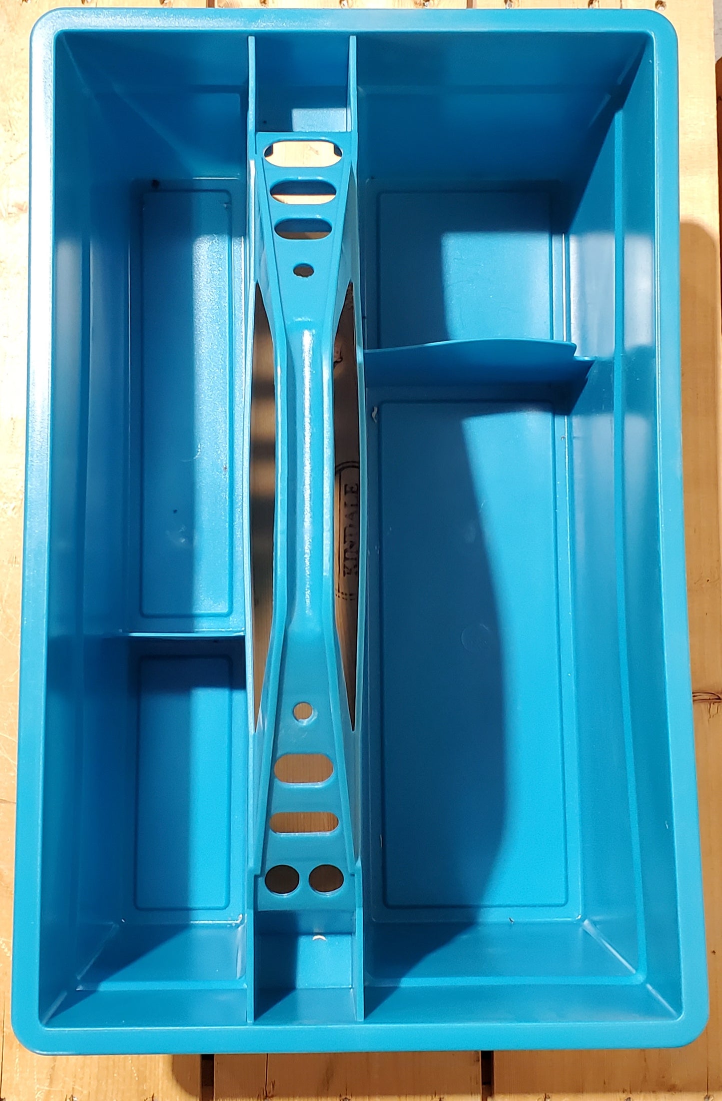 the top of a blue plastic utility tote with a handle, designed to be carried by hand and to fit onto a fence board.
