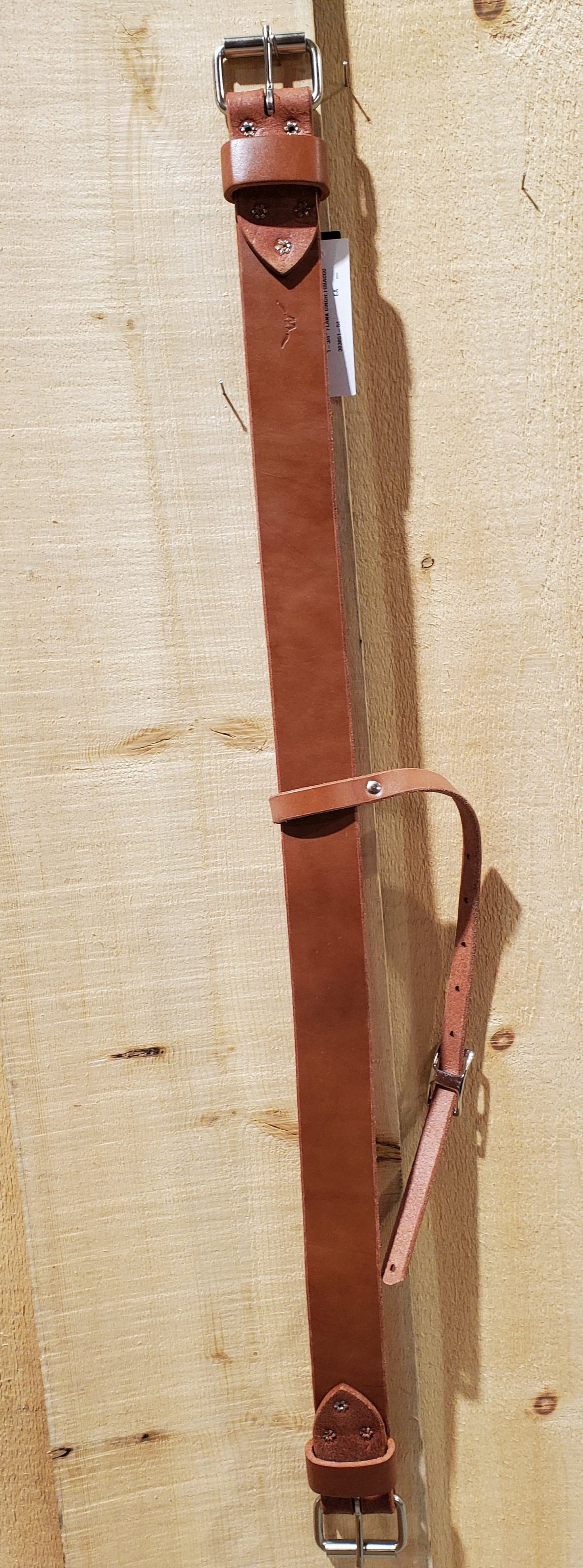 a piece of leather with roller buckles on either end with a strap in the center designed for use on horses to attach to a western saddle