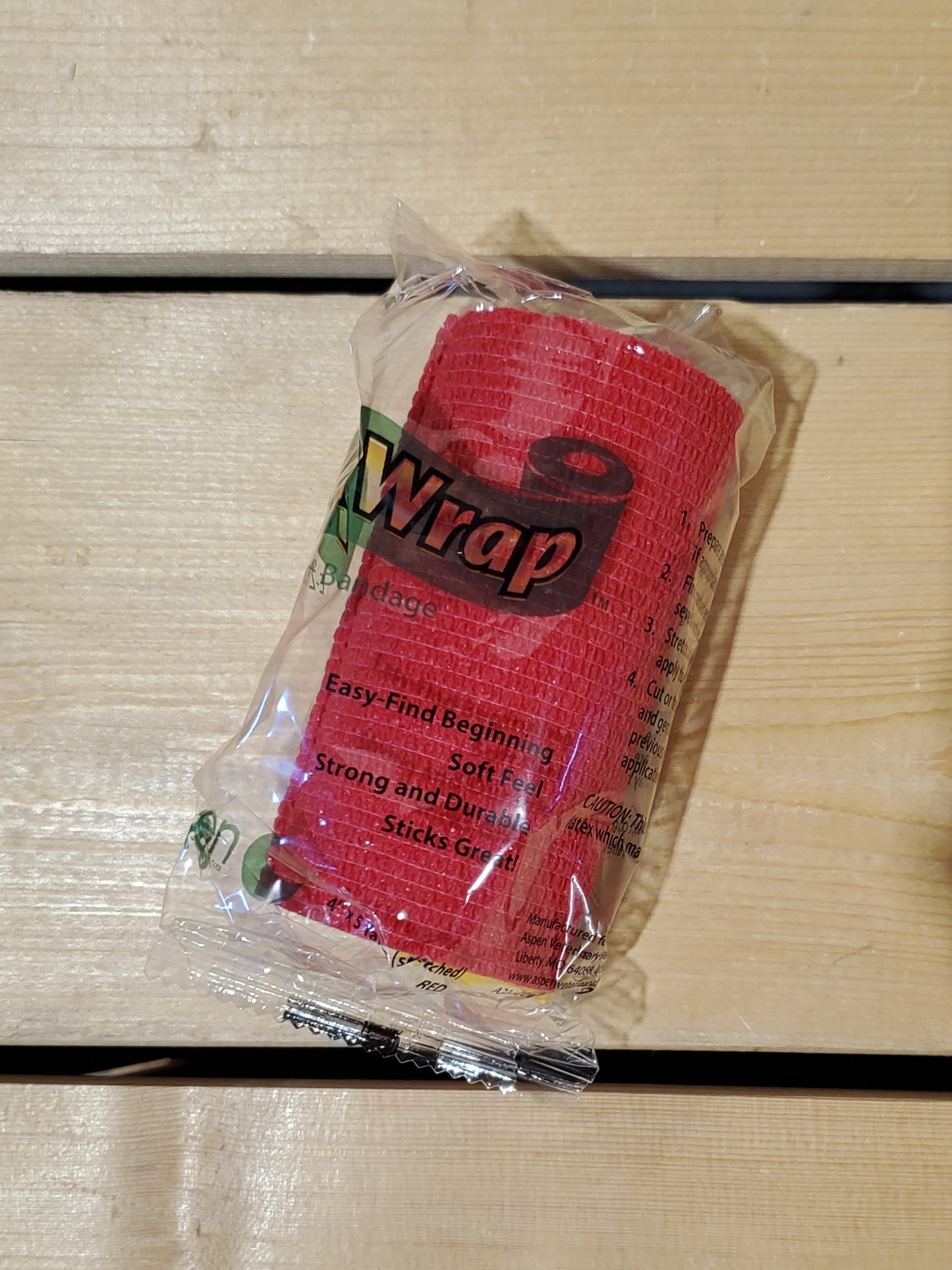 A rolled-up red FlexWrap E-Z Tear bandage, secured with a label that has the product name and details.
