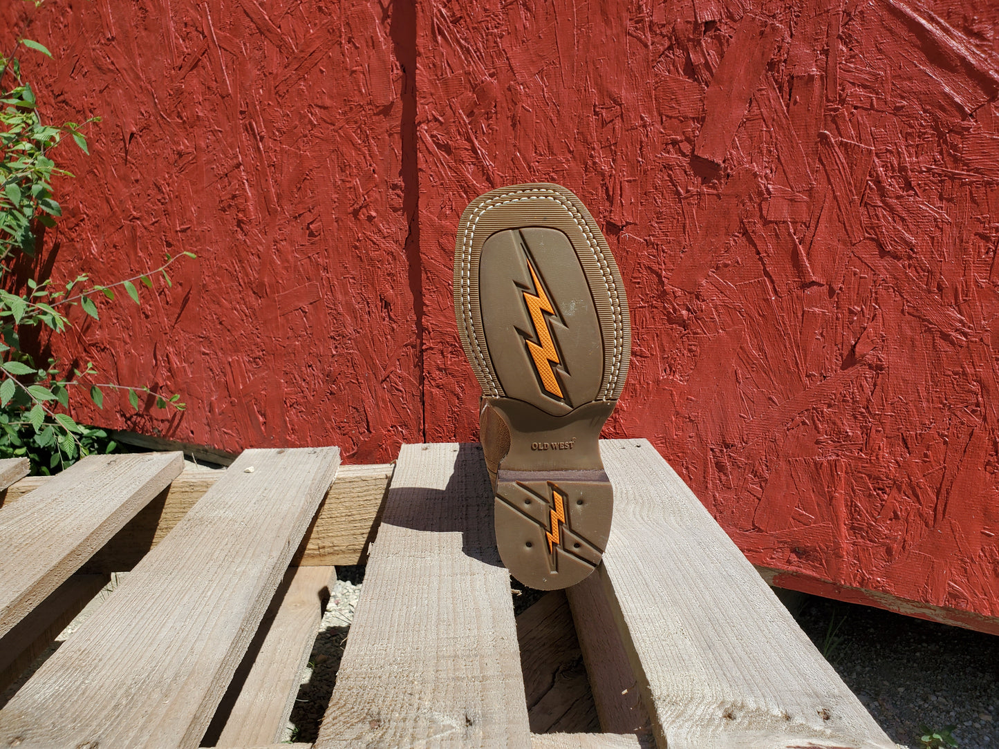 the bottom of a kids cowboy boot on a wooden surface with a red background