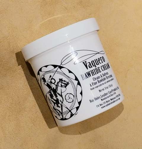 A container of Ray Hole's Vaquero Rawhide Cream with a graphic design on the label on a tan background