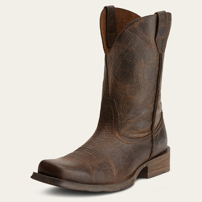 a distressed brown cowboy boot with a boxy square toe on an off white background