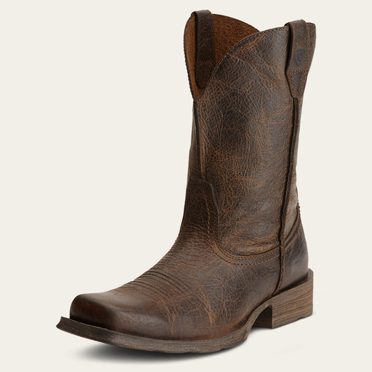 a distressed brown cowboy boot with a boxy square toe on an off white background