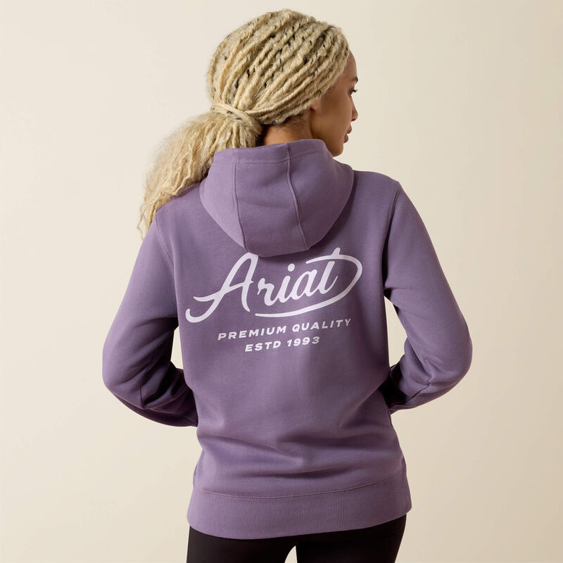 Person wearing a purple Ariat hoodie on a beige background