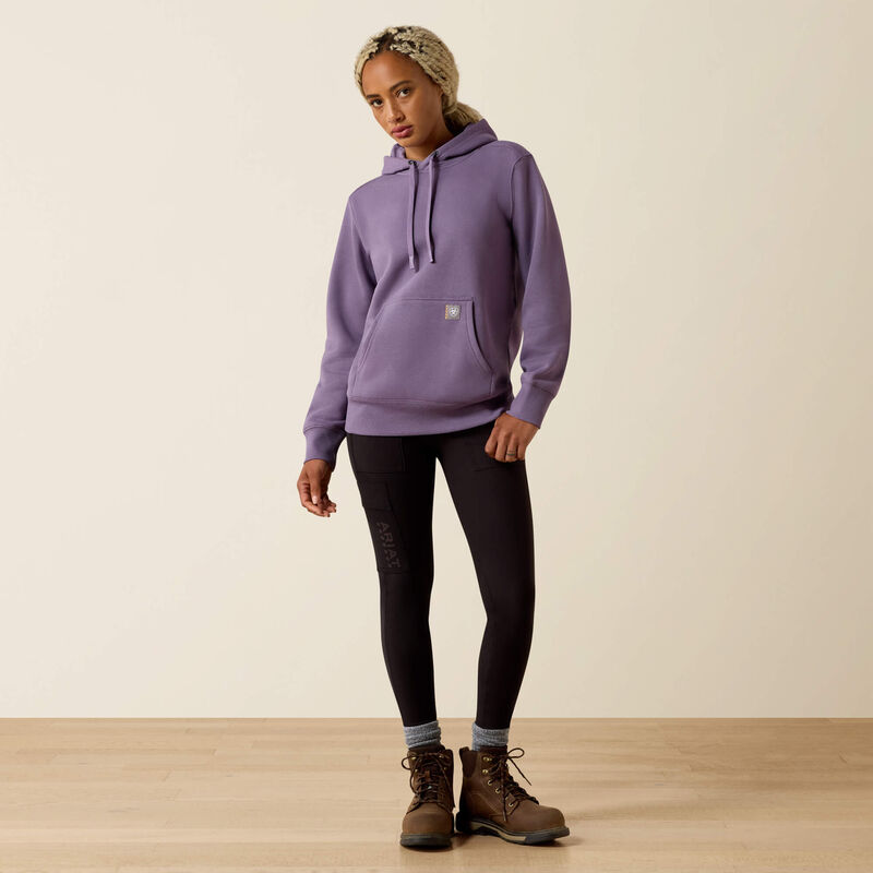 Person wearing a purple Ariat hoodie on a beige background