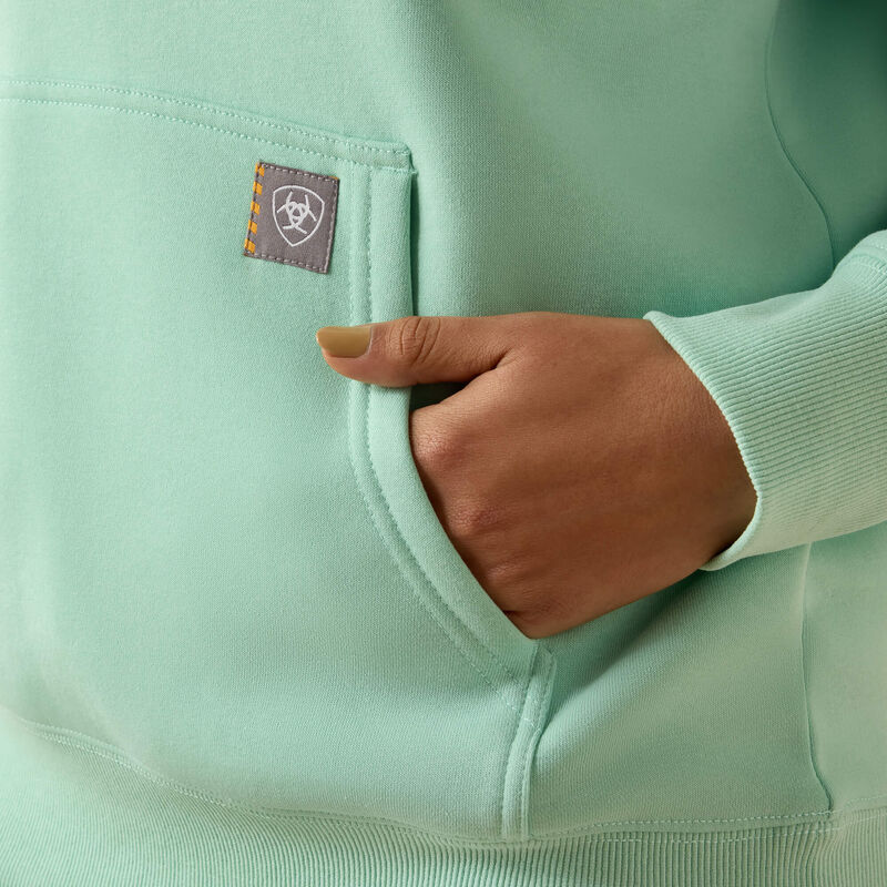 Light green Ariat sweatshirt with a brand logo on the chest pocket, worn by a person.