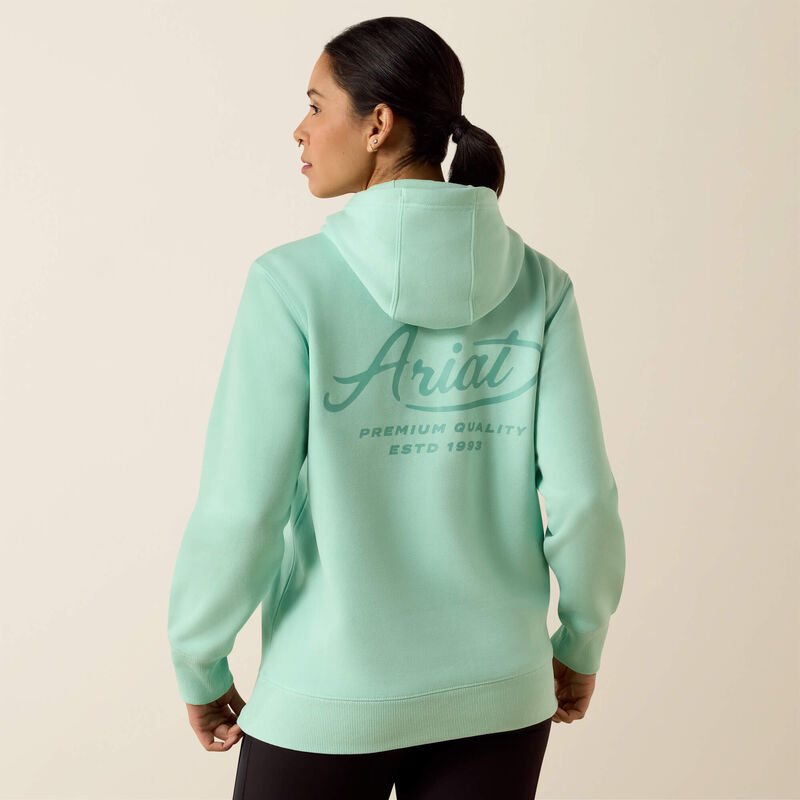 Person wearing a light green Ariat hoodie on a beige background
