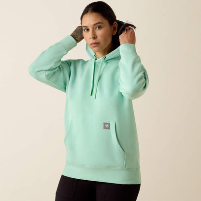 Person wearing a light green Ariat hoodie on a beige background
