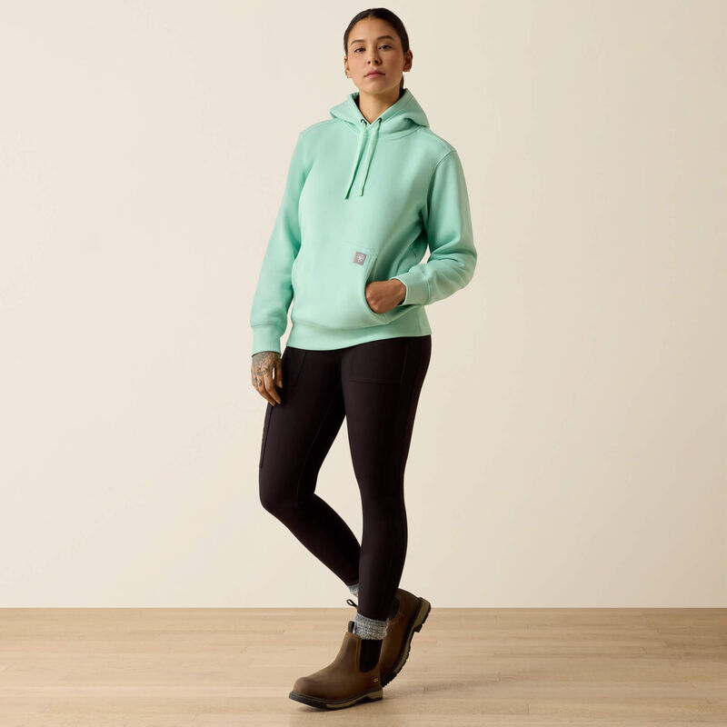 Person wearing a light green Ariat hoodie on a beige background