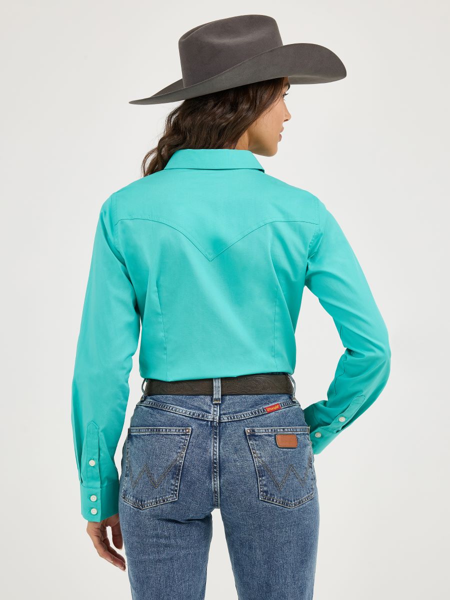 Person wearing a turquoise Wrangler long-sleeve shirt and blue jeans with a gray cowboy hat on a white background