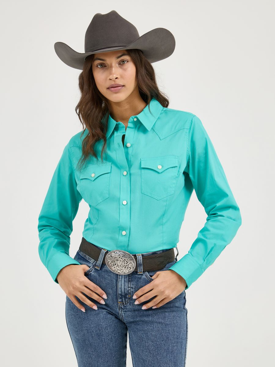 Woman wearing a Wrangler turquoise shirt, jeans, and a gray cowboy hat on a white background