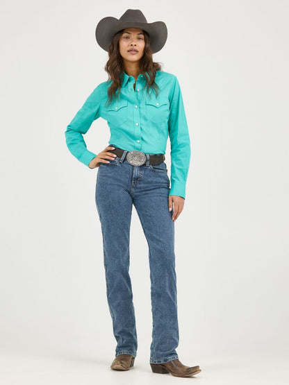 Woman wearing a turquoise Wrangler shirt, blue jeans, and a cowboy hat on a white background