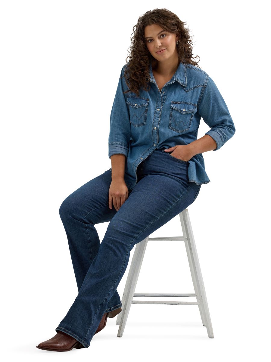 Woman wearing a denim outfit sitting on a stool against a white background