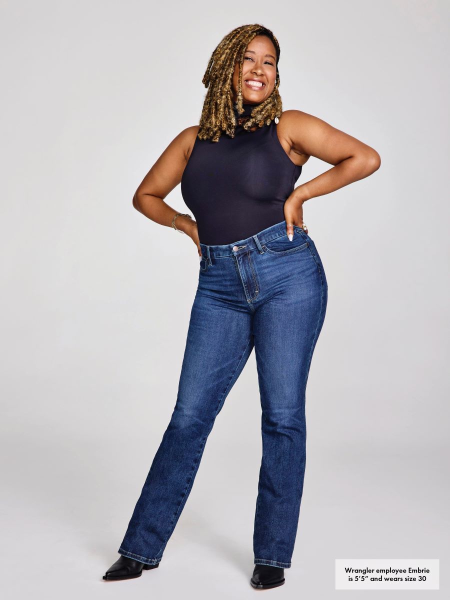 Woman wearing blue jeans and a black top on a white background