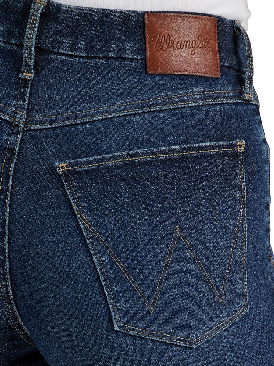 Close-up of blue jeans with a brown leather patch and 'Wrangler' branding.