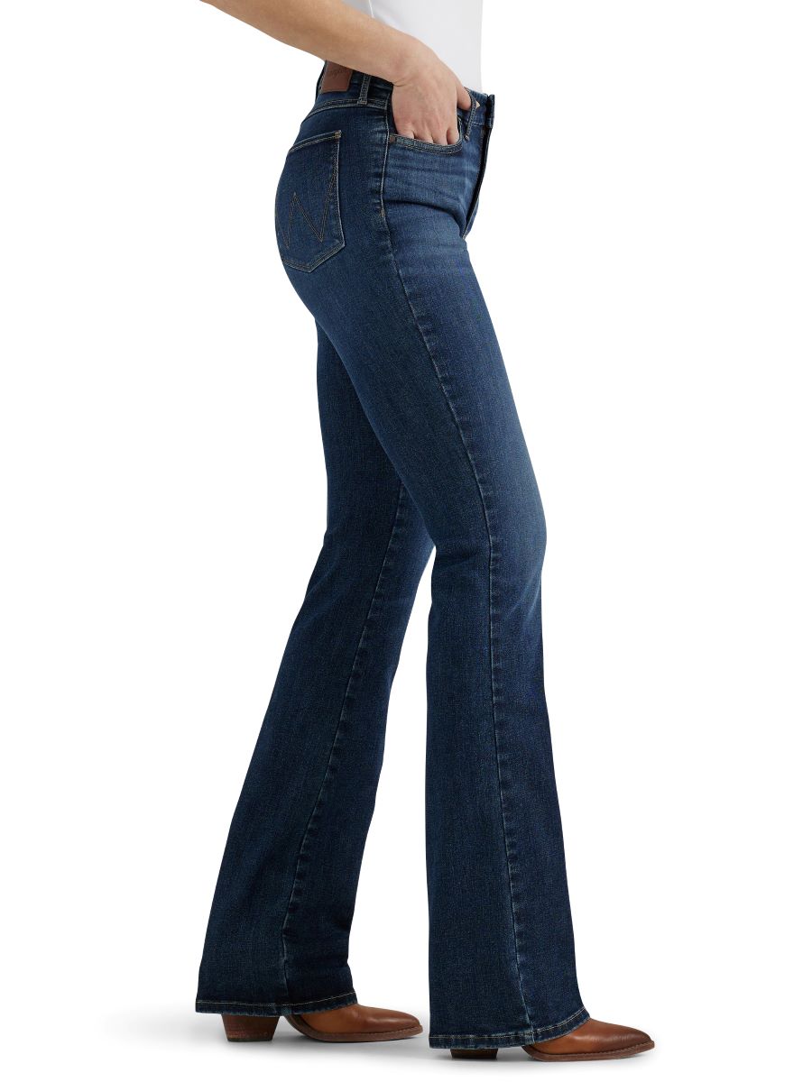 A woman standing with her back towards the camera wearing high-rise boot-cut jeans and a black top.