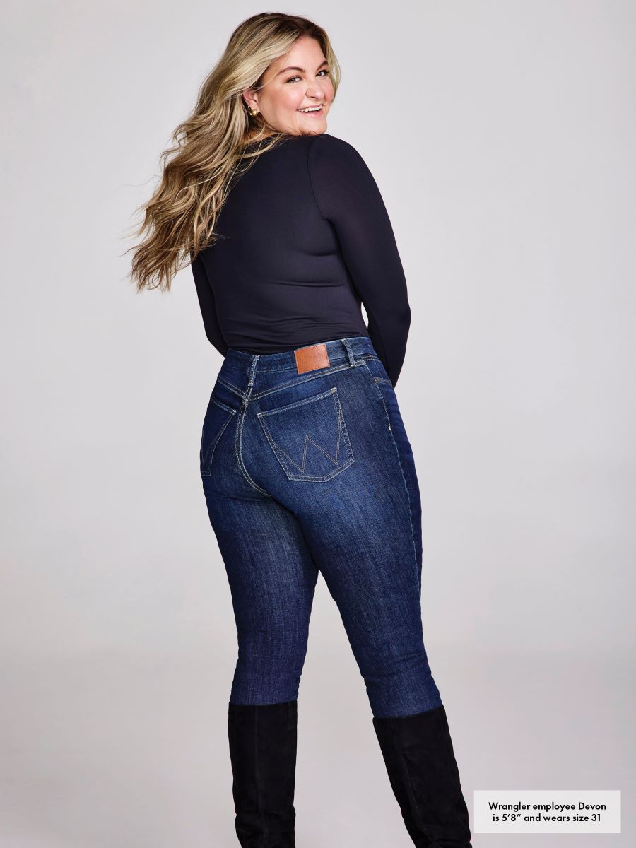 woman wearing blue jeans and a black top on a plain background