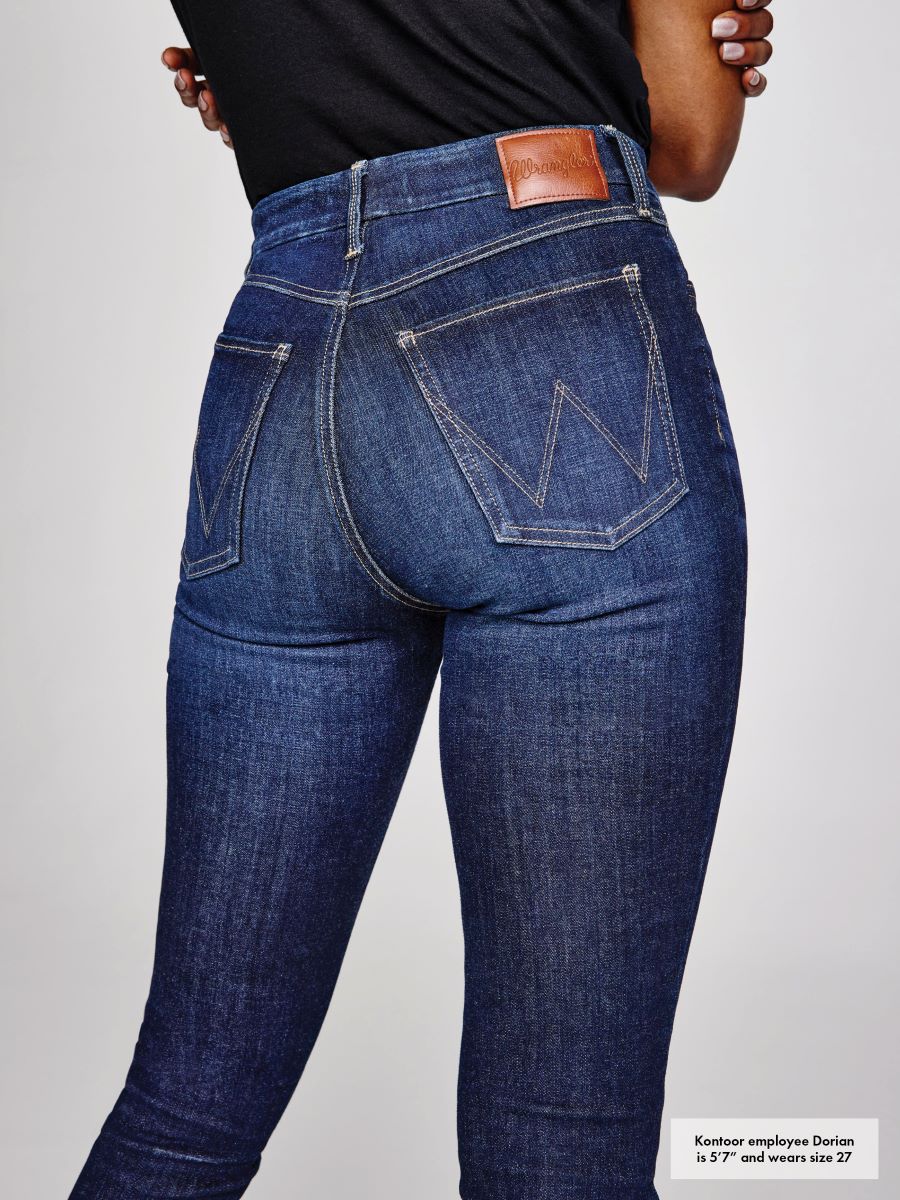 Person wearing blue jeans with a visible brand logo on a light gray background