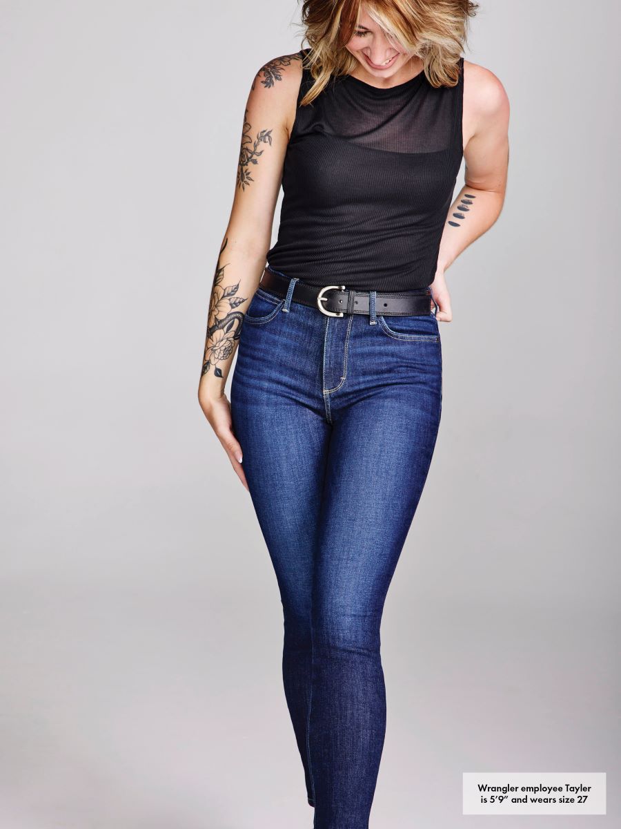 Woman wearing blue jeans and a black top on a gray background