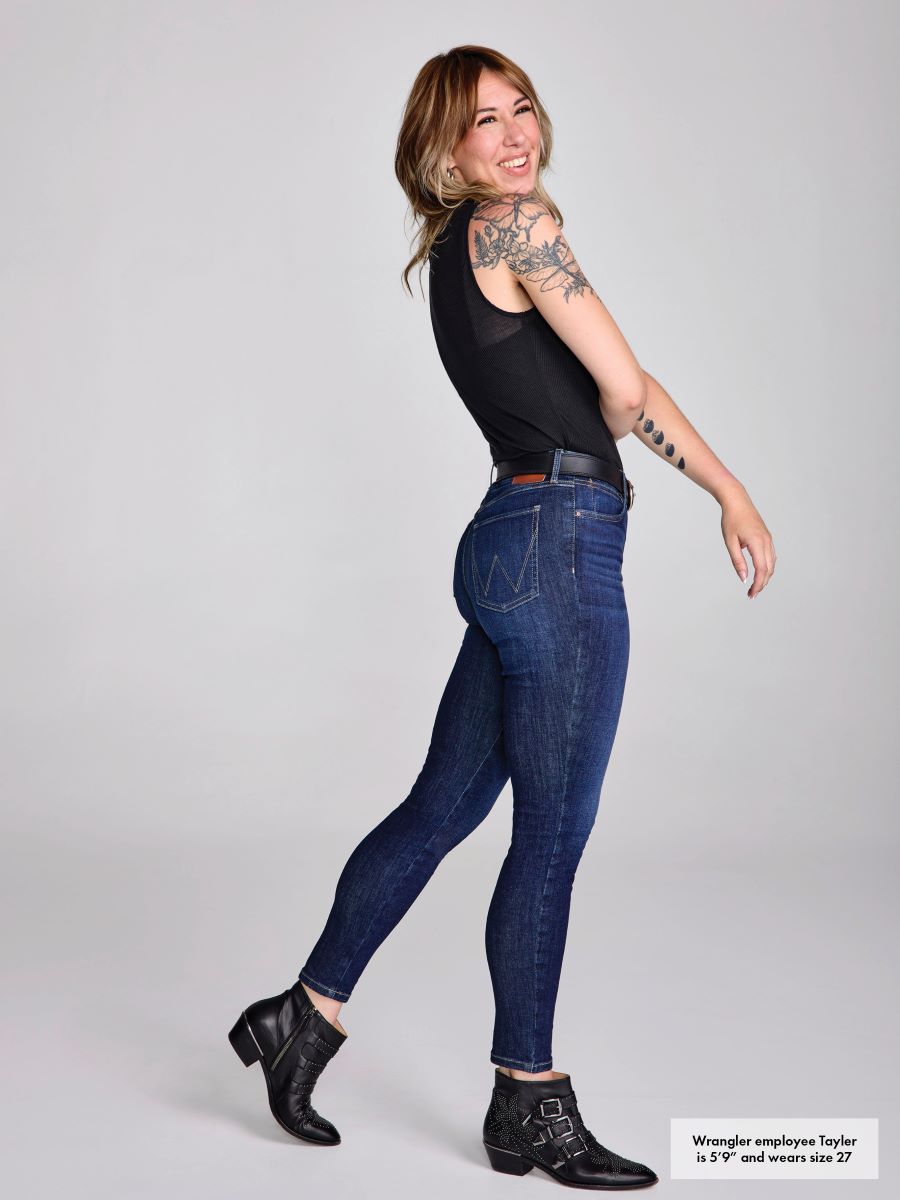 Woman wearing blue jeans and a black top on a gray background