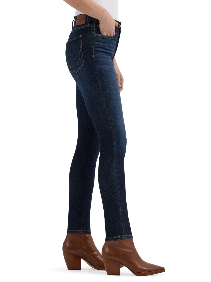Person wearing dark blue jeans and brown boots on a white background