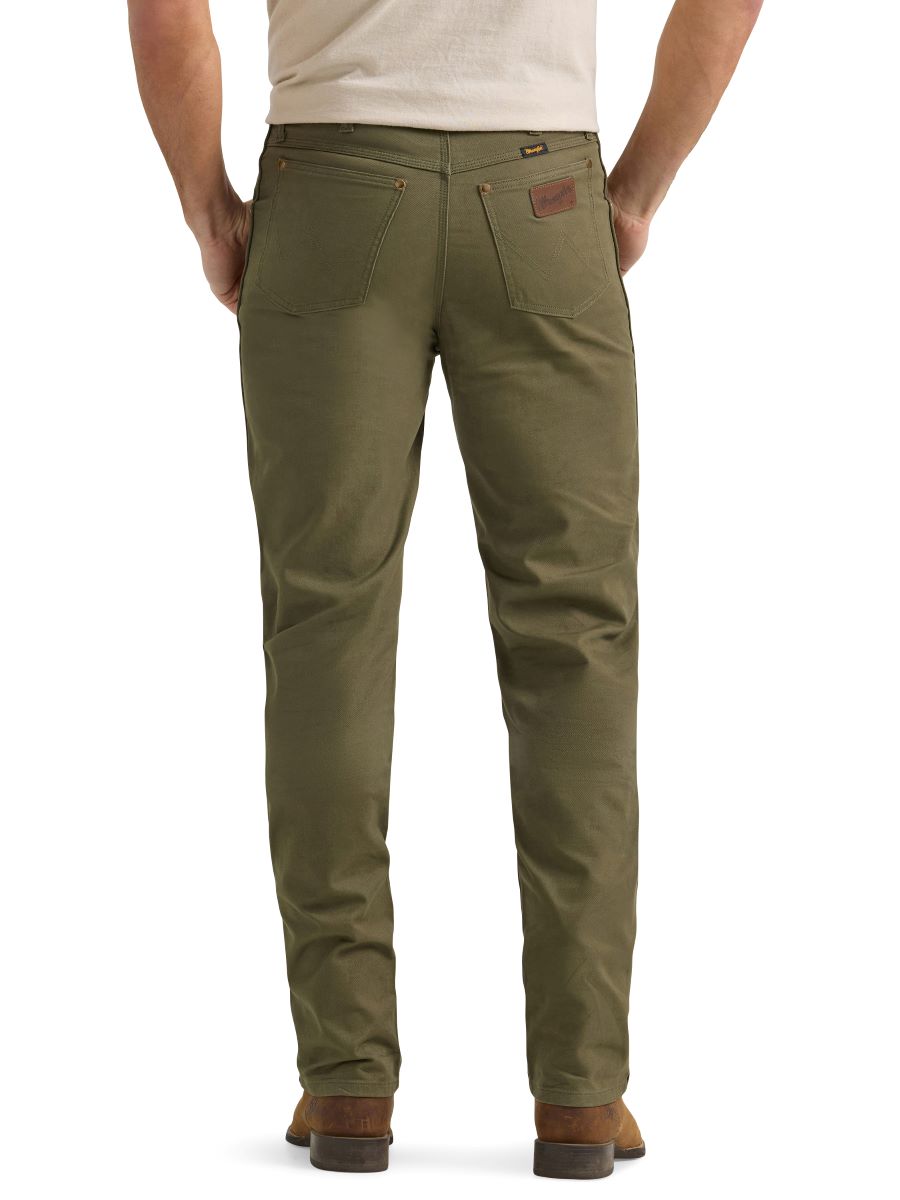 A man wearing a pair of olive green Wrangler cowboy cut canvas jeans and brown boots.