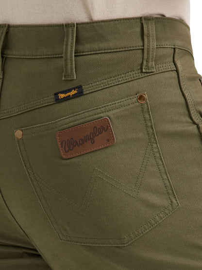 a close up of olive green cowboy cut canvas pants by wrangler with the wrangler leather patch