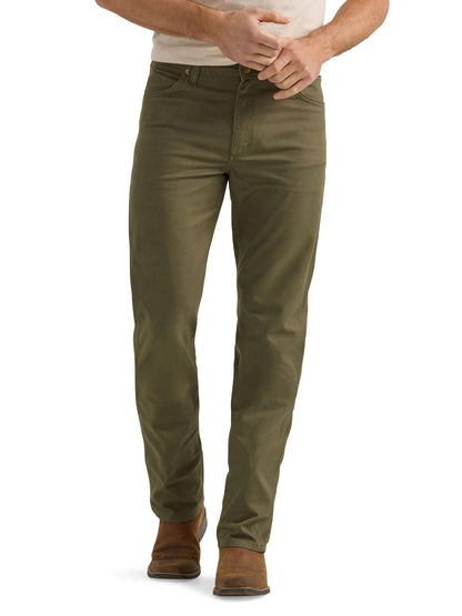 A man wearing a pair of olive green Wrangler cowboy cut canvas jeans and brown boots.