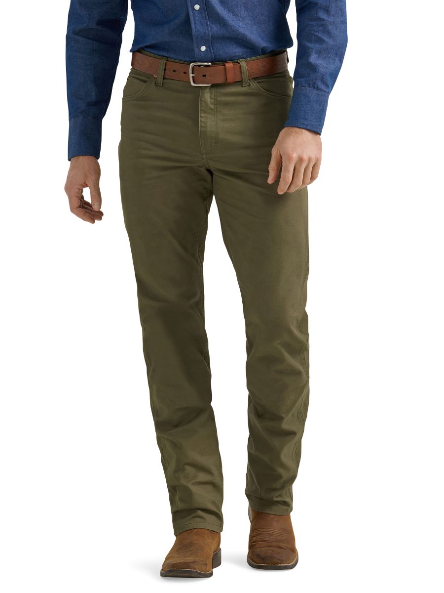 A man wearing a pair of olive green Wrangler cowboy cut canvas jeans and brown boots.
