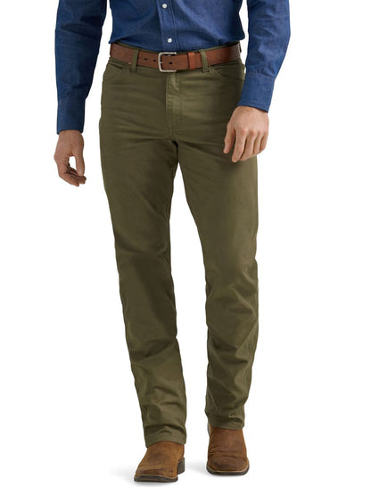 A man wearing a pair of olive green Wrangler cowboy cut canvas jeans and brown boots.