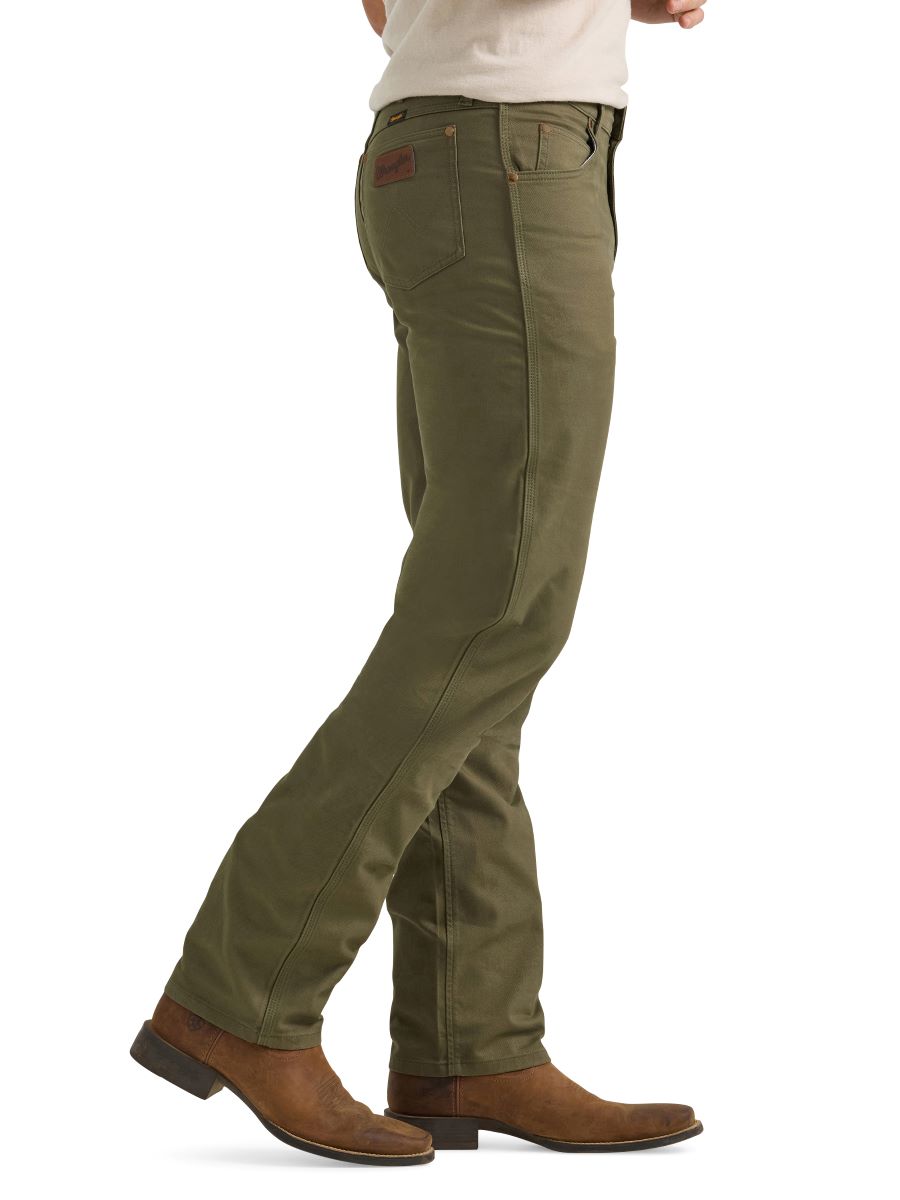 A man wearing a pair of olive green Wrangler cowboy cut canvas jeans and brown boots.
