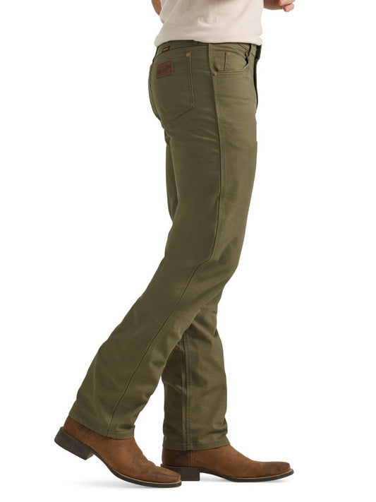 A man wearing a pair of olive green Wrangler cowboy cut canvas jeans and brown boots.