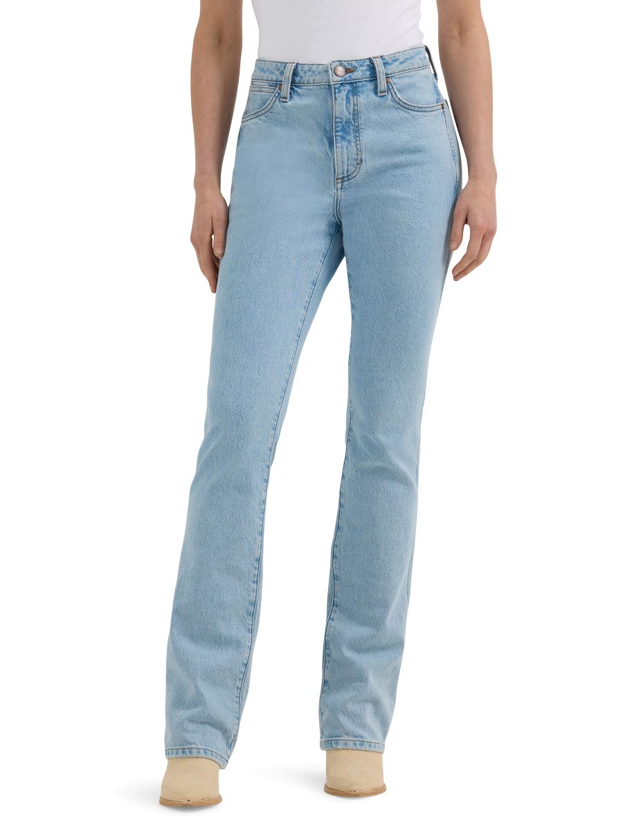 A side view of a woman wearing light wash 'Bailey' high rise boot cut women's jeans by Wrangler, with a leather patch on the pocket and a button closure.