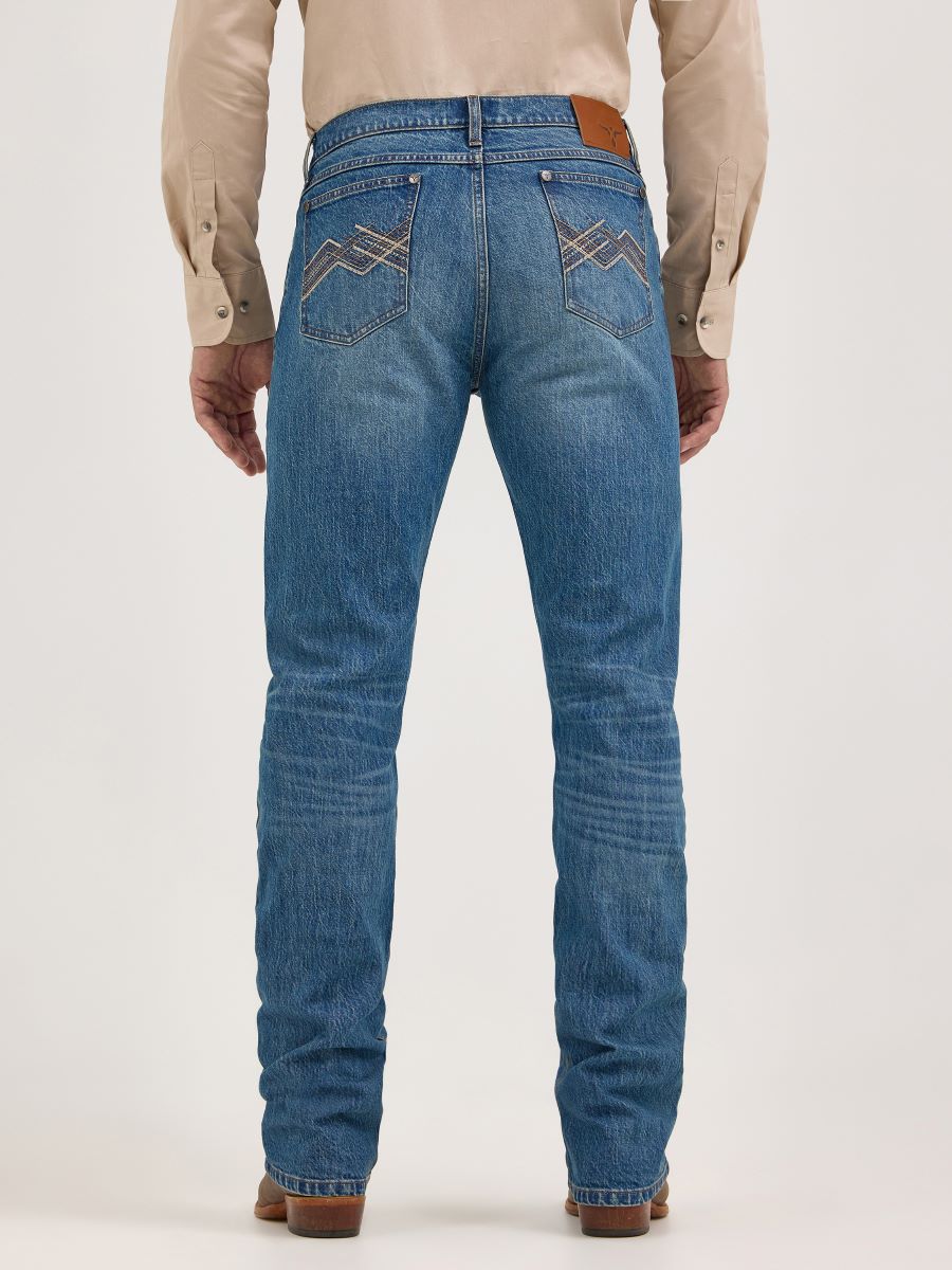 Person wearing blue Wrangler jeans with a beige shirt on a white background