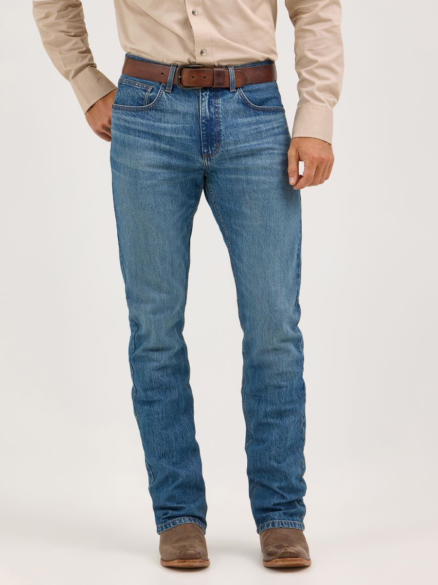 Person wearing blue Wrangler jeans with a brown belt on a white background