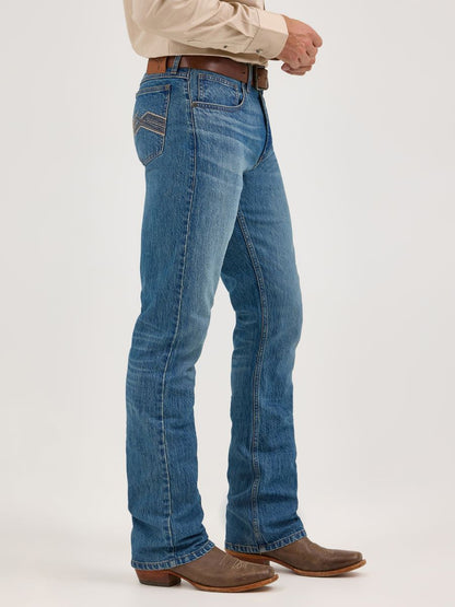 Person wearing blue Wrangler jeans and brown boots on a white background