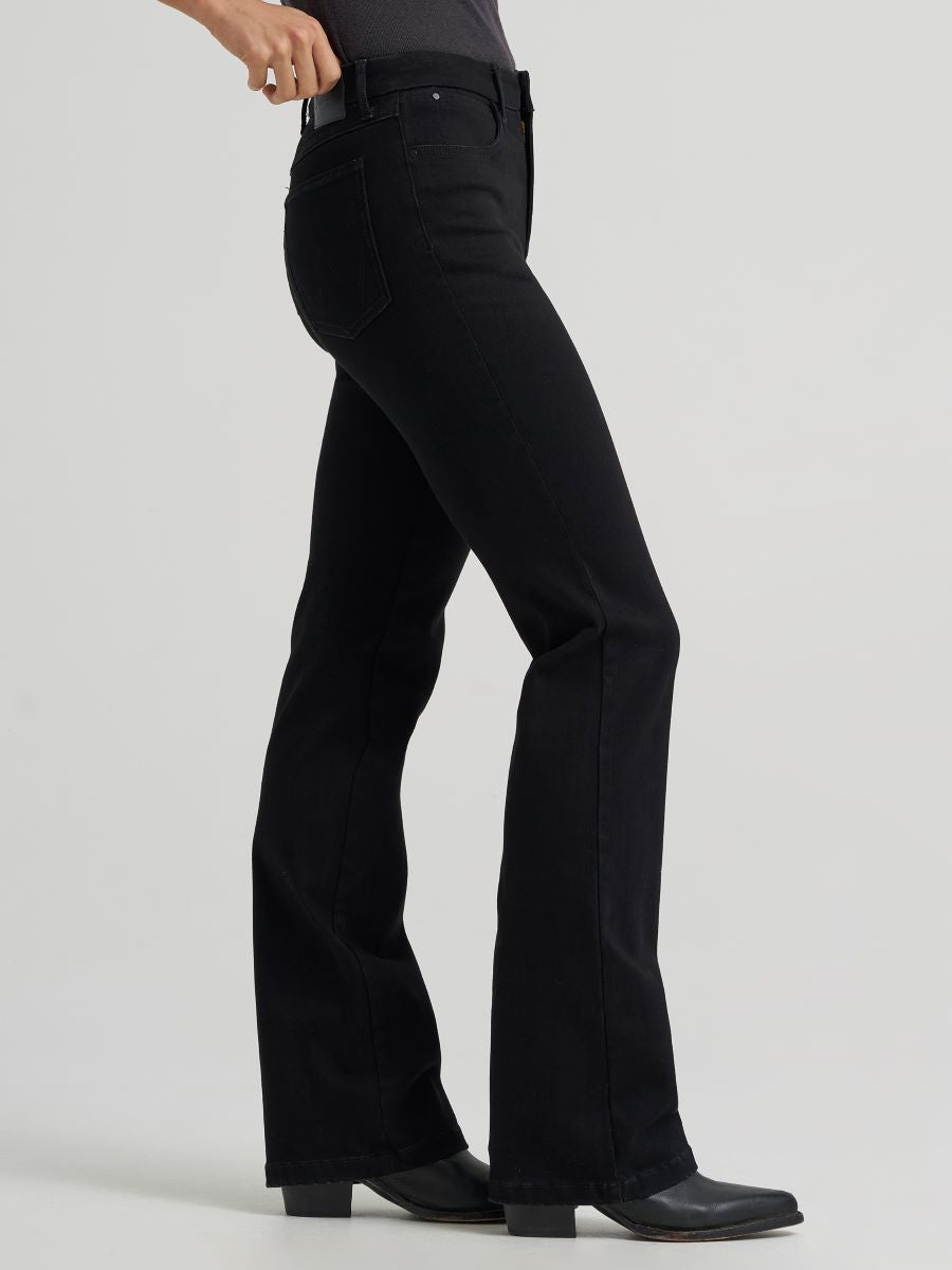 a side view of a woman wearing black jeans and boots on a grey background