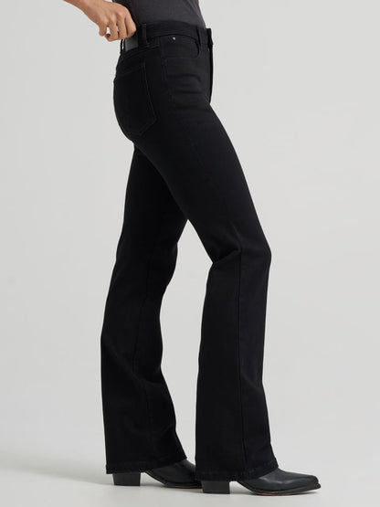 a side view of a woman wearing black jeans and boots on a grey background