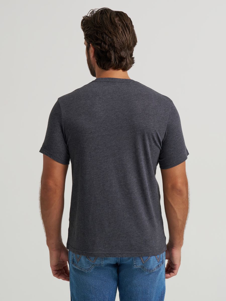 Man wearing a dark gray t-shirt and blue jeans on a light gray background